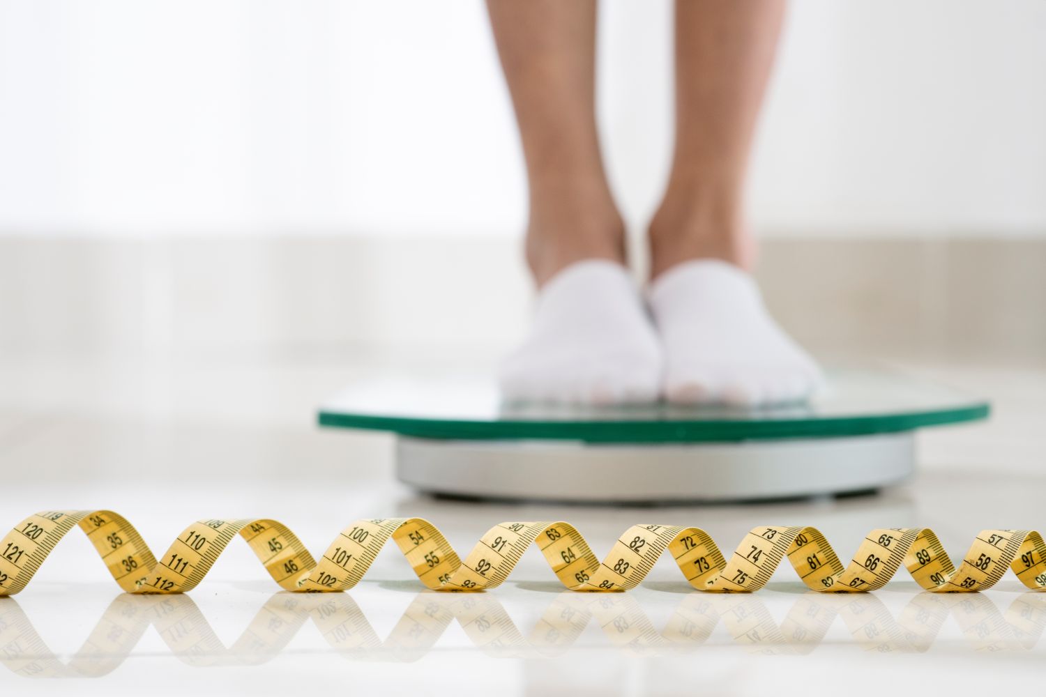 woman on scale with measuring tape